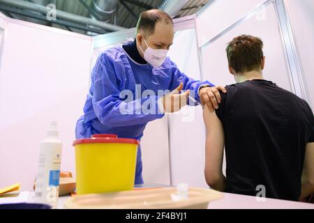 Dresda, Germania. 20 Marzo 2021. Un medico vaccina un giovane con il principio attivo AstraZeneca contro Corona presso il Centro vaccinazioni di Messe Dresden. Lo stato della Sassonia ha ripreso le vaccinazioni con il vaccino AstraZeneca. Questi sono stati interrotti per un breve periodo il 15.03.2021 dopo la comparsa di coaguli di sangue in connessione temporale con le vaccinazioni. Credit: Robert Michael/dpa-Zentralbild/dpa/Alamy Live News Foto Stock