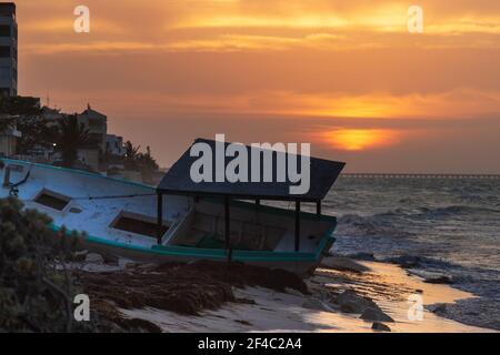 Tramonto sul Golfo del Messico, con una barca punteggiata sulla spiaggia in primo piano. Preso nel febbraio 2020, prima che Covid raggiunga il paese. Foto Stock