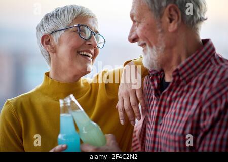 Una felice coppia anziana gustando un drink e trascorrendo il tempo insieme in un'atmosfera allegra. Coniugi, anziani, insieme Foto Stock