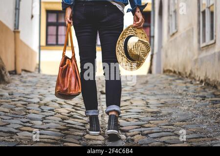 La donna indossa scarpe da ginnastica e cammina per strada nella città vecchia. Gambe umane con scarpe in tela Foto Stock
