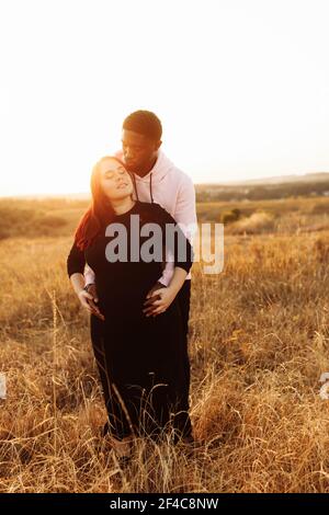 Coppia tenera abbracciando, affascinante uomo afroamericano con adorabile donna bianca che cammina sul campo, trascorrere fine settimana all'aperto, giovane famiglia godere Foto Stock