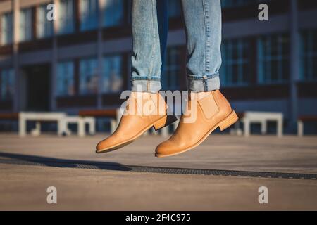 Donna con stivali in pelle che saltano in strada. Levitazione delle gambe femminili Foto Stock