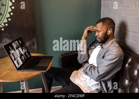 Un dipendente maschile confuso sta utilizzando un computer portatile e sta effettuando una videoconferenza. Uomo d'affari concentrato che parla con i colleghi in riunione on-line, discutere l'azienda Foto Stock