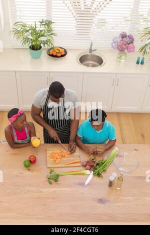 Vista ad alto angolo di padre afroamericano che insegna figlia e. figlio cucina in cucina Foto Stock