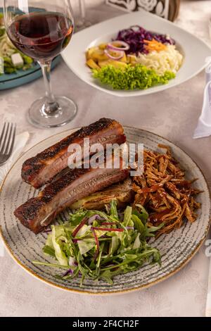Costolette di ricambio piccanti alla griglia servite con lattuga verde fresca al tavolo del ristorante Foto Stock