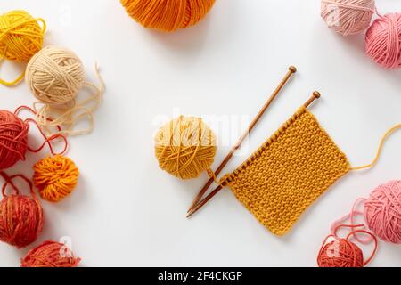 Progetto di lavorazione a maglia in corso. Un pezzo di maglia con sfera di filato e di aghi di tessitura. Foto Stock