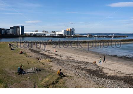 Le persone che si godono il frangiflutti del porto di Granton e la baia di Wardie in una giornata di sole, Edimburgo, Scozia Foto Stock