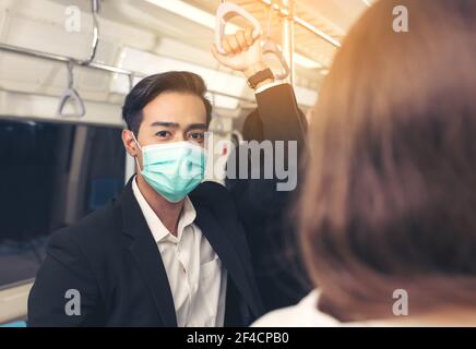 Le persone in treno indossano maschere anti-virus e viaggiano durante le ore di punta. I passeggeri all'interno del treno sopraelevato con le maschere sui volti di tutte le persone. Foto Stock