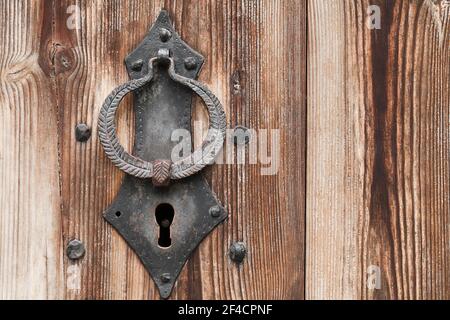 Vecchia toppa forgiata e anello di battuta su una vecchia porta di legno, primo piano foto Foto Stock