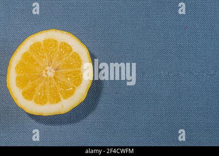 Particolare di limone fresco affettato su un tessuto rustico di tela texture in tonalità chiara di colore tessuto blu Foto Stock