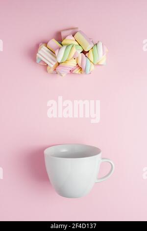 Marshmallow a forma di nuvola piovosa con coppa bianca su sfondo rosa. Concetto creativo minimo di cibo dolce per le vacanze. Foto Stock