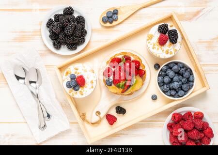Dolci dolci con frutti di bosco freschi su sfondo ligneo. Foto Stock