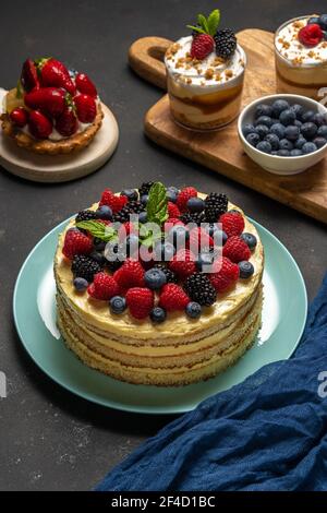 Torta fatta in casa con frutti di bosco freschi e dolci su sfondo scuro. Foto Stock