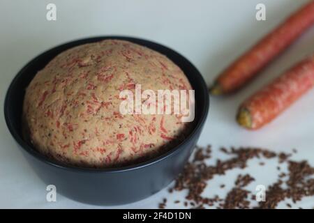 Impasto di grano integrale mescolato con carote grattugiate e semi di lino macinato per la preparazione di pane piatto. Localmente conosciuto come paratha della carota. Foto Stock