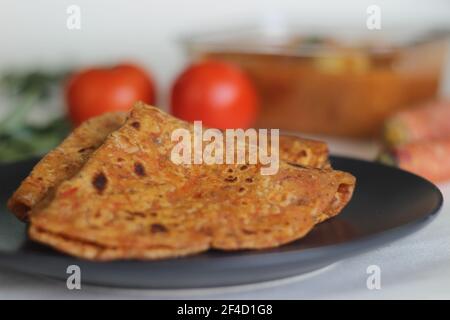 Paratha di semi di lino di carota. Pane piatto indiano fatto di grano intero, carote grattugiate e semi di lino macinato. Scatto su sfondo bianco Foto Stock