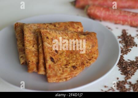 Paratha di semi di lino di carota. Pane piatto indiano fatto di grano intero, carote grattugiate e semi di lino macinato. Scatto su sfondo bianco Foto Stock