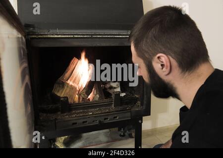 Un primo piano di un uomo caucasico che inizia un fuoco nel camino. Foto Stock
