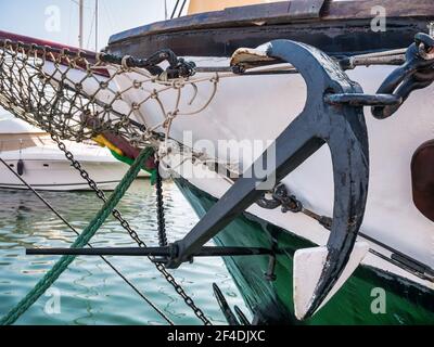 Vecchio ancoraggio retrò legato con catena in acciaio e funi da una vecchia nave nel porto Foto Stock