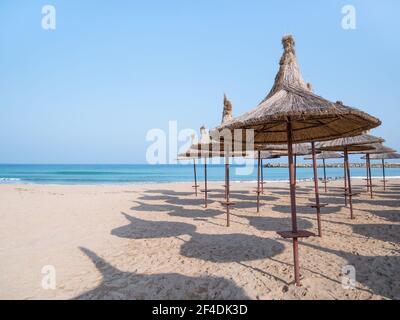 Paesaggio estivo con ombrelloni di paglia sulla spiaggia di Mangalia o Mamaia. Spiaggia sul Mar Nero in Romania. Foto Stock