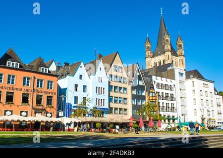 Colonia, Germania - 27 settembre 2018: Paesaggio con vecchi edifici colorati sul fiume Reno arginato con la grande chiesa di San Martino Foto Stock