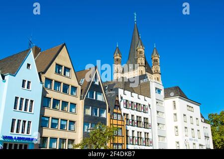 Colonia, Germania - 27 settembre 2018: Paesaggio con vecchi edifici colorati sul fiume Reno arginato con la grande chiesa di San Martino Foto Stock