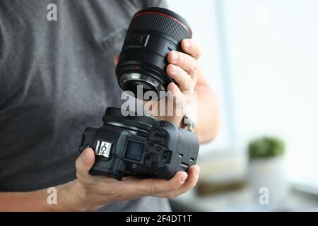 Mani maschili che indossano l'obiettivo professionale della fotocamera digitale moderna Foto Stock