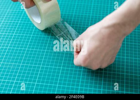 le mani che tengono e un[[steso nastro adesivo sulla superficie Foto Stock