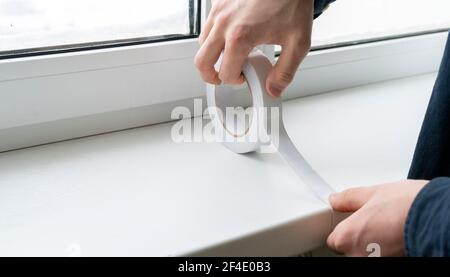 le mani che tengono e un[[steso nastro adesivo sulla superficie Foto Stock