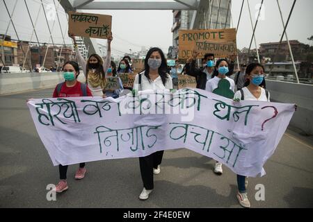 Kathmandu, Nepal. 19 marzo 2021. Gli attivisti ambientali marciano con un'enorme bandiera durante la manifestazione contro la decisione di costruire l'aeroporto internazionale di Nijgadh a Bara, che si ritiene possa portare al taglio di alberi e alla perdita di biodiversità. L'aeroporto è a circa 80 chilometri (50 miglia) a sud della capitale del Nepal. Si stima che 2.4 milioni di alberi dovranno essere abbattiti per costruire l'aeroporto, che si prevede costerà 3.5 miliardi di dollari. Credit: Prabin Ranabhat/SOPA Images/ZUMA Wire/Alamy Live News Foto Stock