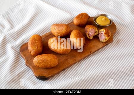 Mini cani da mais fatti in casa su una rustica tavola di legno, vista laterale. Foto Stock