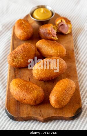 Mini cani da mais fatti in casa su una rustica tavola di legno, vista laterale. Foto Stock