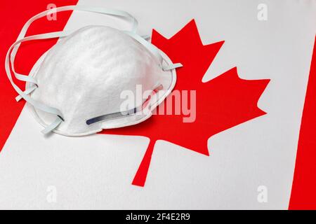 Bandiera Canada e maschera facciale N95. Concetto di Covid-19 coronavirus blocco, divieto di viaggio e crisi sanitaria Foto Stock