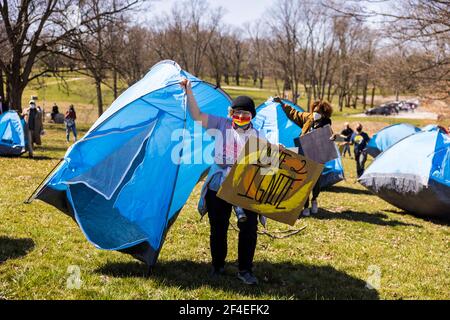 Un protetore porta una tenda intaccata come parte di una protesta nei campi di coda vicino al Memorial Stadium. Una coalizione di membri della comunità di Bloomington, attivisti, E gli studenti dell'Indiana University marciano da Dunn Meadow alla Simon Skjodt Assembly Hall durante la "marcia per la fine della follia" per protestare contro il trattamento della città di Bloomington per i residenti non ospitati che lanciano tende sulla proprietà pubblica e il pagamento di 10 milioni di dollari di cessazione Indiana University dovrà pagare licenziato Allenatore da basket da uomo Archie Miller. All'interno di Assembl si giocavano diversi giochi per il torneo di basket NCAA Foto Stock