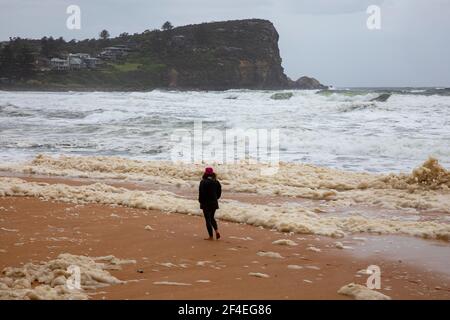 Avalon Beach, Sydney, Australia 21 marzo 2021.As inondazioni battter nuovo Galles del Sud la costa orientale surf batte la costa. La Signora cammina attraverso la schiuma di mare che si trova sulla spiaggia. Foto Stock