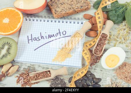Ingredienti nutritivi e iscrizione hashimoto scritta in blocco note. Alimenti sani contenenti vitamine. Problemi con concetto di tiroide Foto Stock