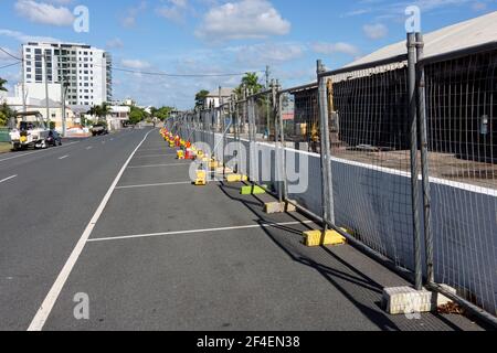 Una linea di recinzioni temporanee con basi gialle in cemento erette di fronte ad un sito di demolizione in una città regionale. Foto Stock