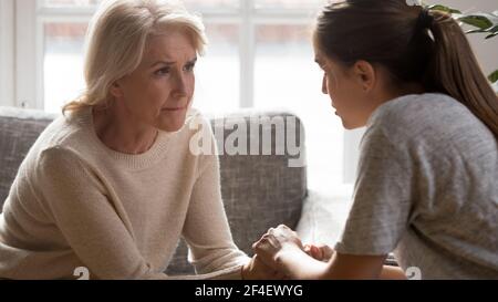 La figlia che si prende cura di crescere conforta la madre più anziana infelice Foto Stock