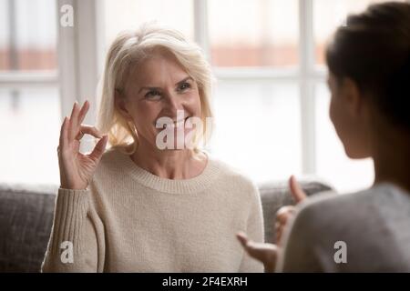 Donna anziana felice parlare utilizzando il linguaggio dei segni Foto Stock