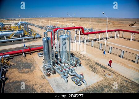 Regione di Aktobe/Kazakhstan - Maggio 04 2012: Impianto di raffinazione del petrolio nel deserto. Panorama. Tubi rossi, apparecchiature metalliche e valvole rosse. Lavoratore di raffineria in wo rosso Foto Stock