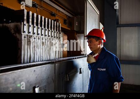 Taldykorgan, Kazakhstan - Giugno 06 2012: Impianto di riciclaggio degli accumulatori Kainar. Giovane lavoratore asiatico che utilizza una macchina per il riciclaggio dell'elettrolisi. Foto Stock