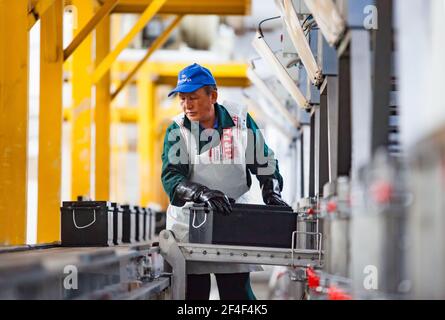 Taldykorgan, Kazakhstan - Giugno 06 2012: Impianto di riciclaggio degli accumulatori Kainar. Lavoratore asiatico riempire batteria di assedio di acido solforico. Foto Stock