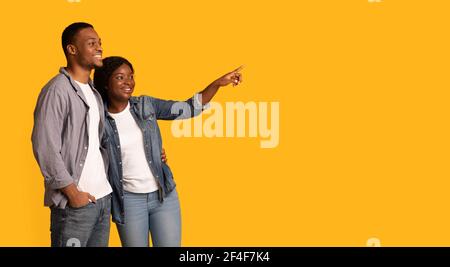 Giovane coppia nera felice che punta con il dito da parte a Copy Spazio Foto Stock