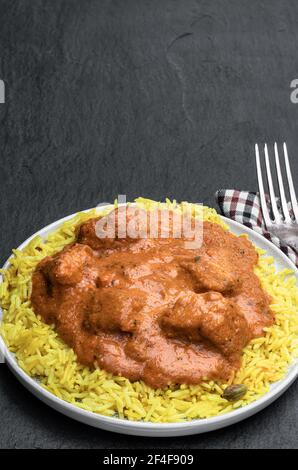 Pollo Tikka Masala con riso pilau su fondo di pietra nera Foto Stock