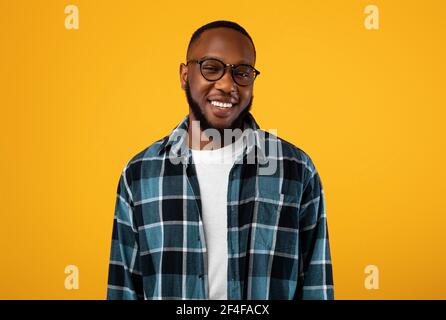 Ritratto di allegro Black Millennial Guy in posa su sfondo giallo Foto Stock