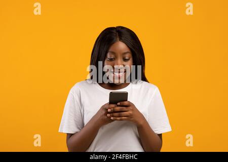 Gioiosa donna afroamericana che usa il telefono cellulare Foto Stock