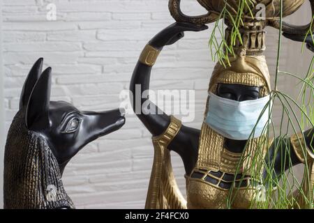 Ancora vita di statue di mitologia jackal anubis inpu anup e la statua di Cleopatra di un servo nubiano con una maschera contro il virus. Foto Stock