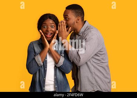 Segreto di condivisione. Black Guy gossiping con la sua ragazza eccitata Foto Stock