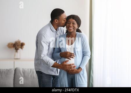 Amore nero uomo baciare la sua moglie incinta Foto Stock