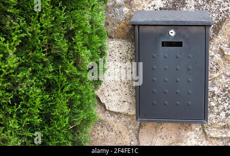 Cassetta postale in metallo nero attaccata sulla casa a muro cottage. Concetto di comunicazione rurale Foto Stock