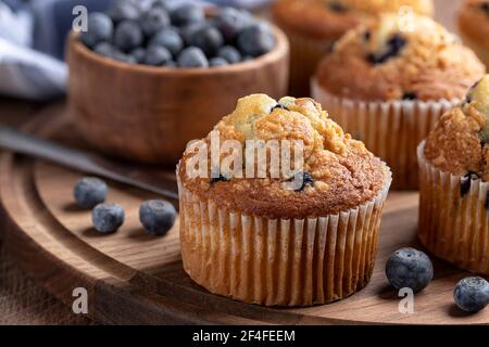 Primo piano di un muffin al mirtillo con frutti di bosco freschi su un piatto di legno Foto Stock